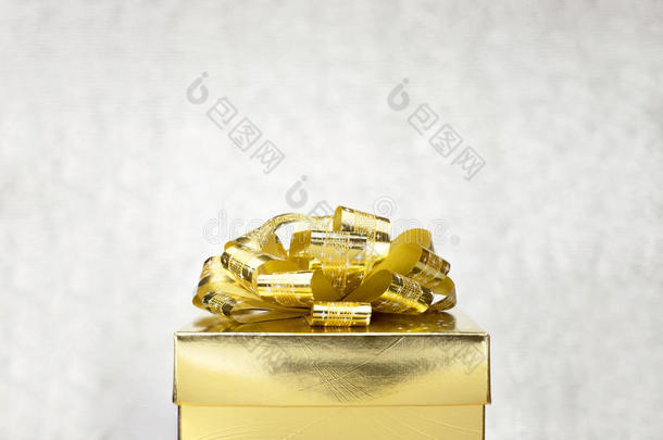 在白模糊背景下，用大<strong>蝴蝶结</strong>关闭<strong>金色</strong>礼品盒，在顶部留出空间添加您的内容