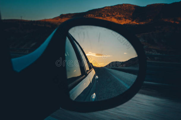 汽车镜子，蓝天和红色的太阳在道路上