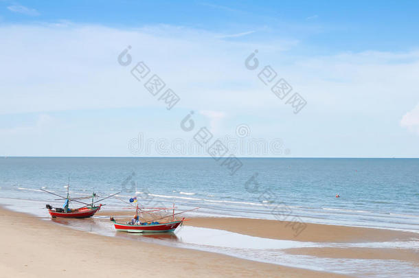 两艘木制渔船都在海滩上，天空湛蓝