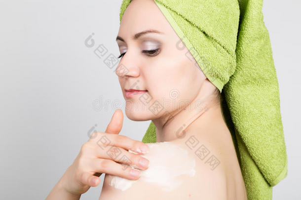 漂亮的年轻女人穿着浴巾在脸上做化妆面具。 美容行业和家庭护肤
