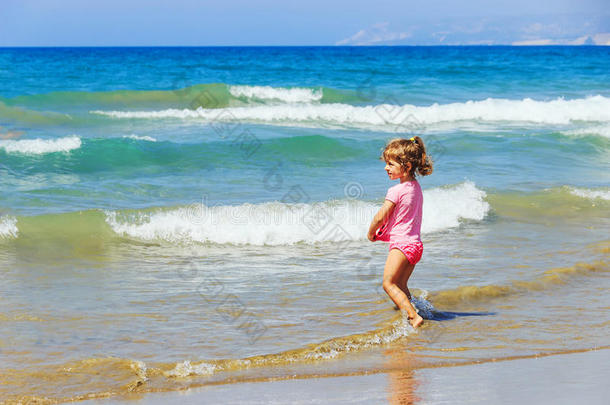 在一个阳光明媚的日子里，可爱的小女孩在海上的浪花中玩耍