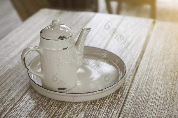 古老的金属茶壶和底板在木制桌子的角落，装饰复古风格，淡淡的效果增加