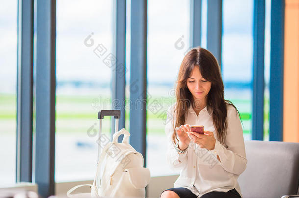 在机场休息室等待飞行飞机的女乘客。 机场有手机的女人的剪影