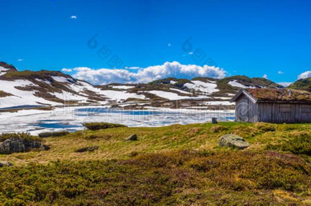 美丽的挪威融化湖与传统的木制小屋在挪威