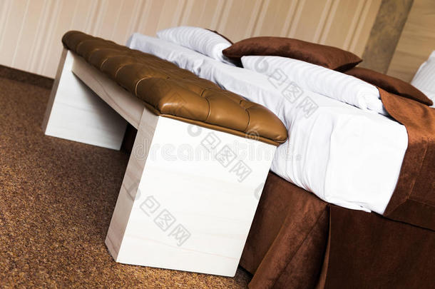 棕色软垫皮革脚凳在床上
