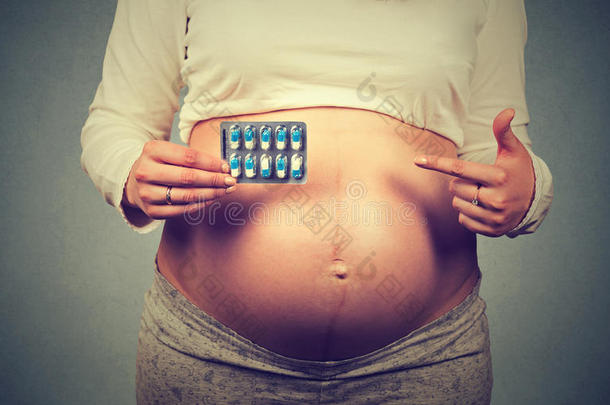 特写镜头裁剪图像孕妇大肚子指着药丸