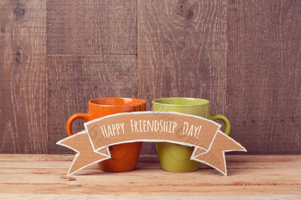 木桌上有纸板横幅的咖啡杯。 友谊日庆祝活动