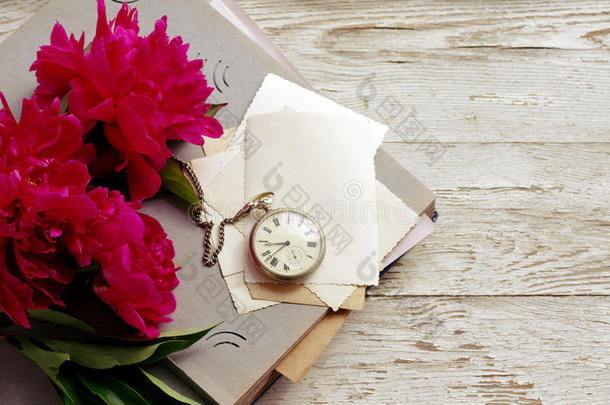 一束粉红色的牡丹花，旧的相册，旧的空照片和一只怀表