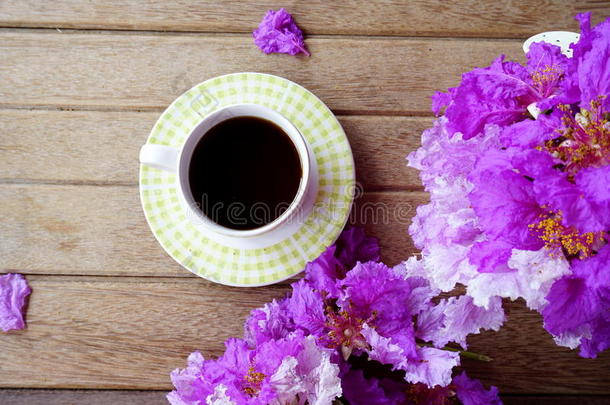 一杯在木制背景上有春天<strong>紫色花</strong>朵的咖啡