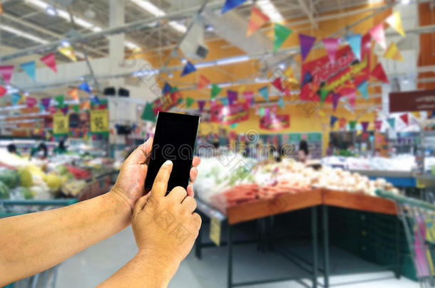 亚洲手拿着智能手机在模糊的购物中心。