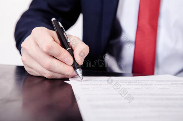 商人签订合同。 一只手拿着一支钢笔，正要签一封信。 造型和少量的
