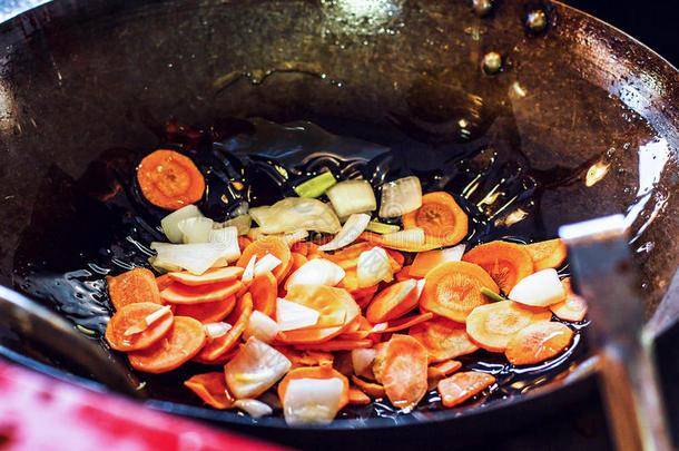 新鲜切片蔬菜：洋葱和胡萝卜，用橄榄油在锅里烤，或在厨房的锅里烤。 烹饪的概念。