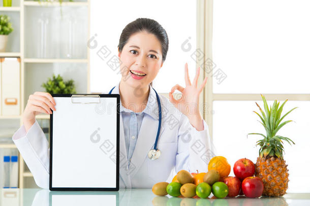 医生营养师与水果持有空白剪贴板和OKS
