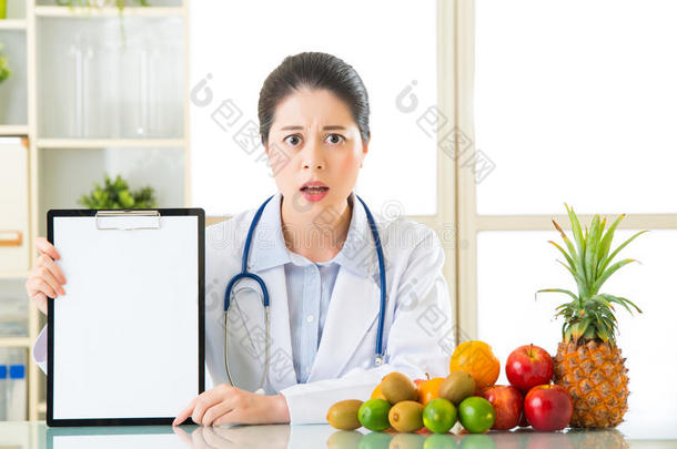 医生营养师拿着水果和空白剪贴板摔倒了