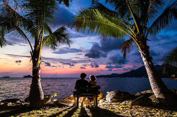 一对夫妇的剪影拥抱和观看日落在海滩上的太阳，浪漫