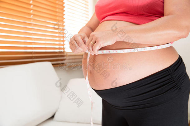 一个正在测量她腰部的孕妇。