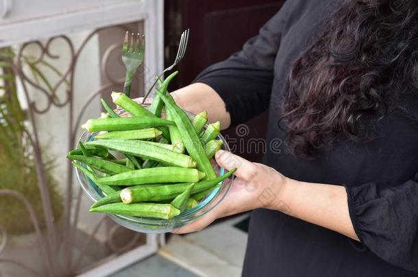 新鲜的绿色女士手指或<strong>秋葵蔬菜</strong>在碗里，人的手拿着碗