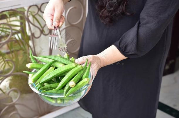 新鲜的绿色女士手指或秋葵蔬菜在碗里，人的手拿着碗