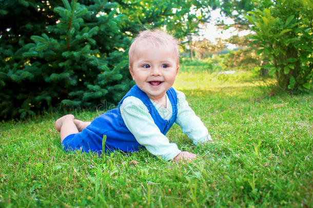 可爱微笑的小婴儿躺在公园里的一棵新鲜的青草上