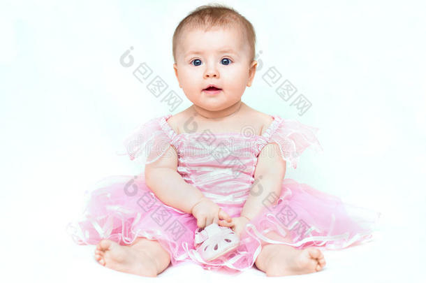 可爱的小女孩穿着粉红色的裙子玩她的粉红色鞋子