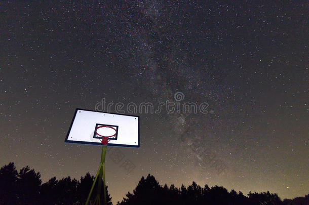 星空下的篮球圈和篮板。银河系。夜空中的篮球场。