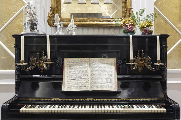 带有蜡烛和乐谱的古董钢琴。 室内装饰。