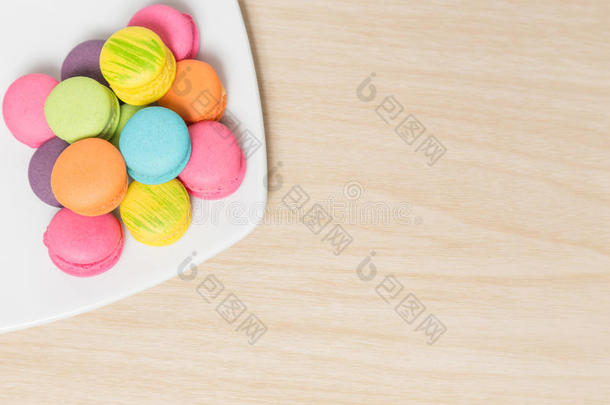 彩色马卡龙饼干在盘子上的木材与复制空间