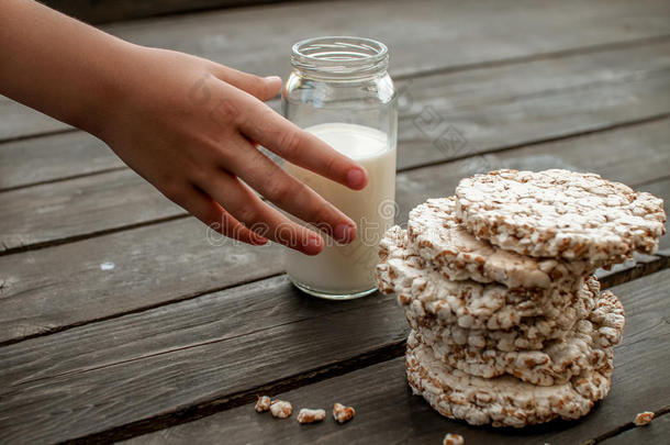 孩子的手把牛奶<strong>带回家</strong>。 美味的脆饼在木制背景桌子上