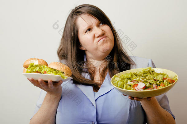 肥胖的白人女人在汉堡包和沙拉之间有选择