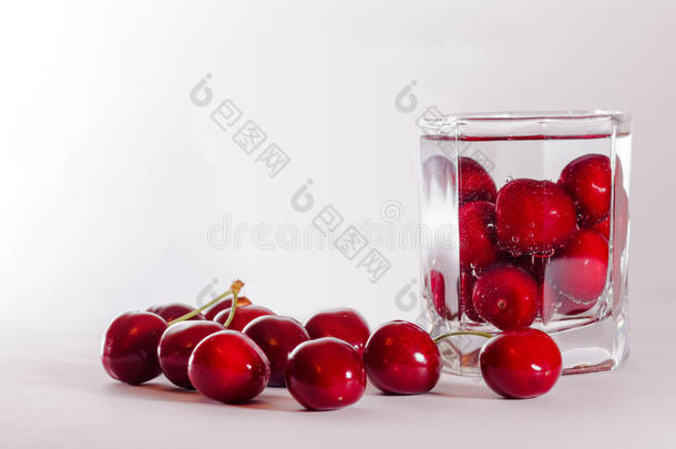 玻璃杯里的樱桃和旁边的一把樱桃