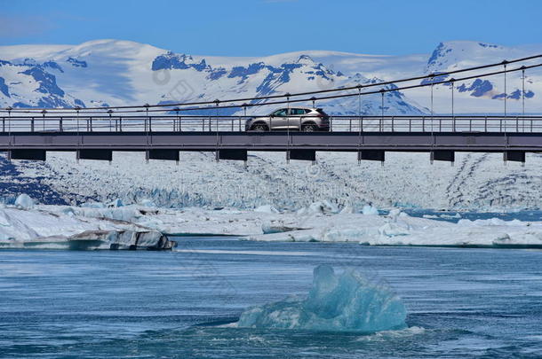 蓝色冰山漂浮在Jokulsarlon冰川泻湖的一辆路过的汽车下面