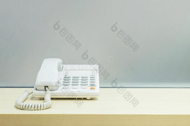 特写白色电话，办公室电话在模糊的木桌和<strong>磨砂玻璃</strong>墙纹理背景在房间在办公室