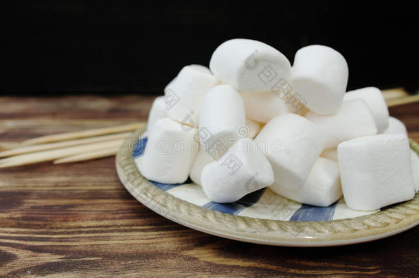 毛茸茸的白色棉花糖在旧木桌上的木碗里