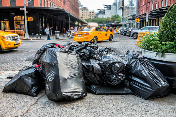 纽约市街道人行道上的黑色垃圾袋等待服务垃圾卡车。 垃圾装在大垃圾袋里准备好了