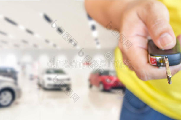 手的人与汽车钥匙在模糊照片汽车展厅