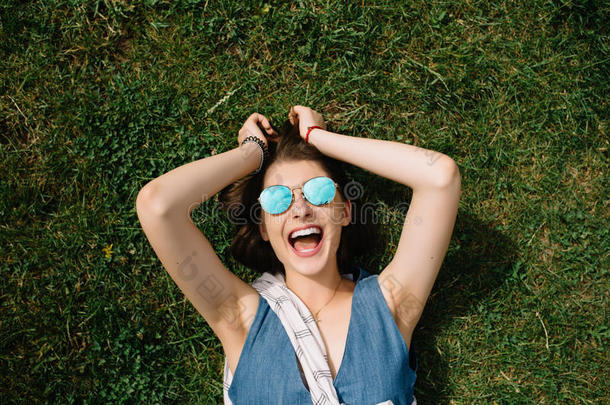 夏天，在城市公园，戴着太阳镜的女孩躺在草地上
