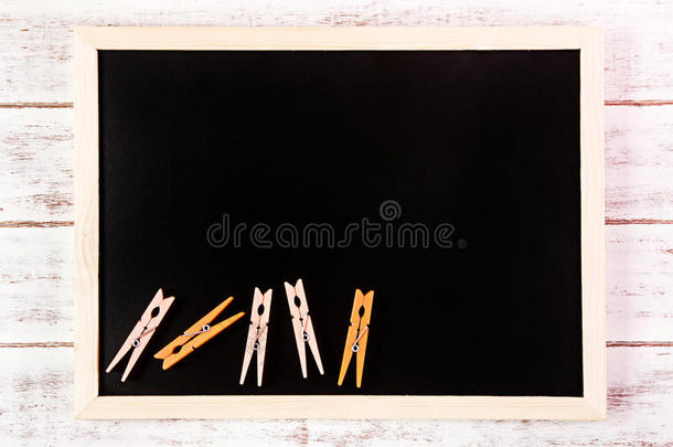 空白黑板和橙色衣服钉在木制桌子上。模板模拟添加您的设计，并在框架旁边留出空间