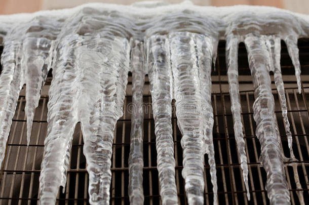 <strong>寒冷天气</strong>的概念与冰柱向下喷在金属网上。 宏观观点。 柔和的焦点