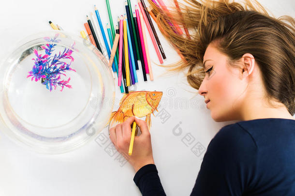 可爱的年轻女艺术家把一张小金鱼的照片特写。 上面的风景