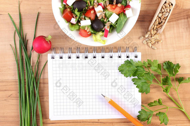 新鲜希腊沙拉配蔬菜，厘米和记事本写笔记，健康营养和减肥概念