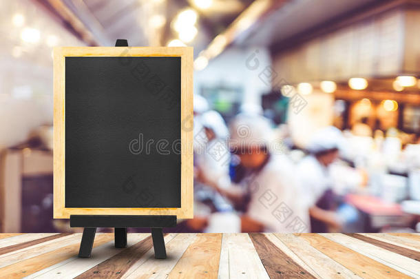 黑板菜单与画架在木桌上与模糊开放厨房在餐厅背景，复制空间添加您的内容