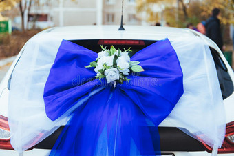 一辆用玫瑰装饰的黑色婚车。 用鲜花和丝带装饰的豪华婚礼车图片