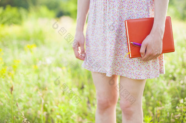 穿着夏装的女孩拿着一本书。