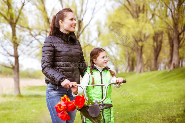 女儿和母亲骑着自行车沿着湖边散步，交谈。 家庭<strong>价值观</strong>教育