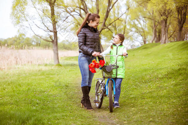 女儿和母亲骑着自行车沿着湖边散步，交谈。 家庭价值观教育