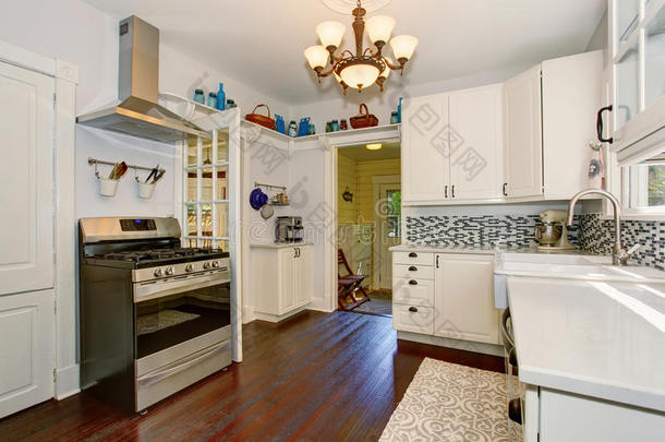 明亮的厨房房间，白色橱柜和硬木地板。