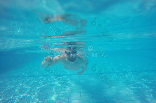 戴眼镜的胡子男人在游泳池里的水下游泳