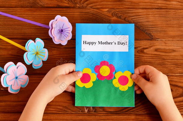 孩子手里拿着一张卡片。 快乐的母亲和#x27；的一天。 一束花。 儿童和#x27；的手工艺为母亲和#x27；的一天