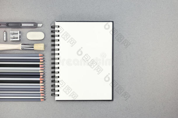 灰色书桌上有<strong>铅笔</strong>和其他<strong>绘图</strong>附件的空白笔记本