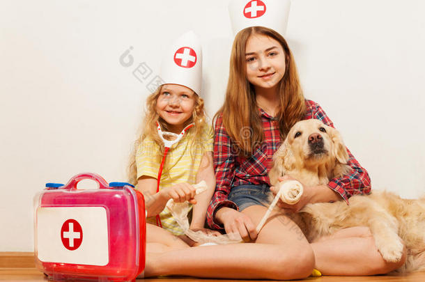 女孩们扮演可爱的医生给他们的宠物狗包扎